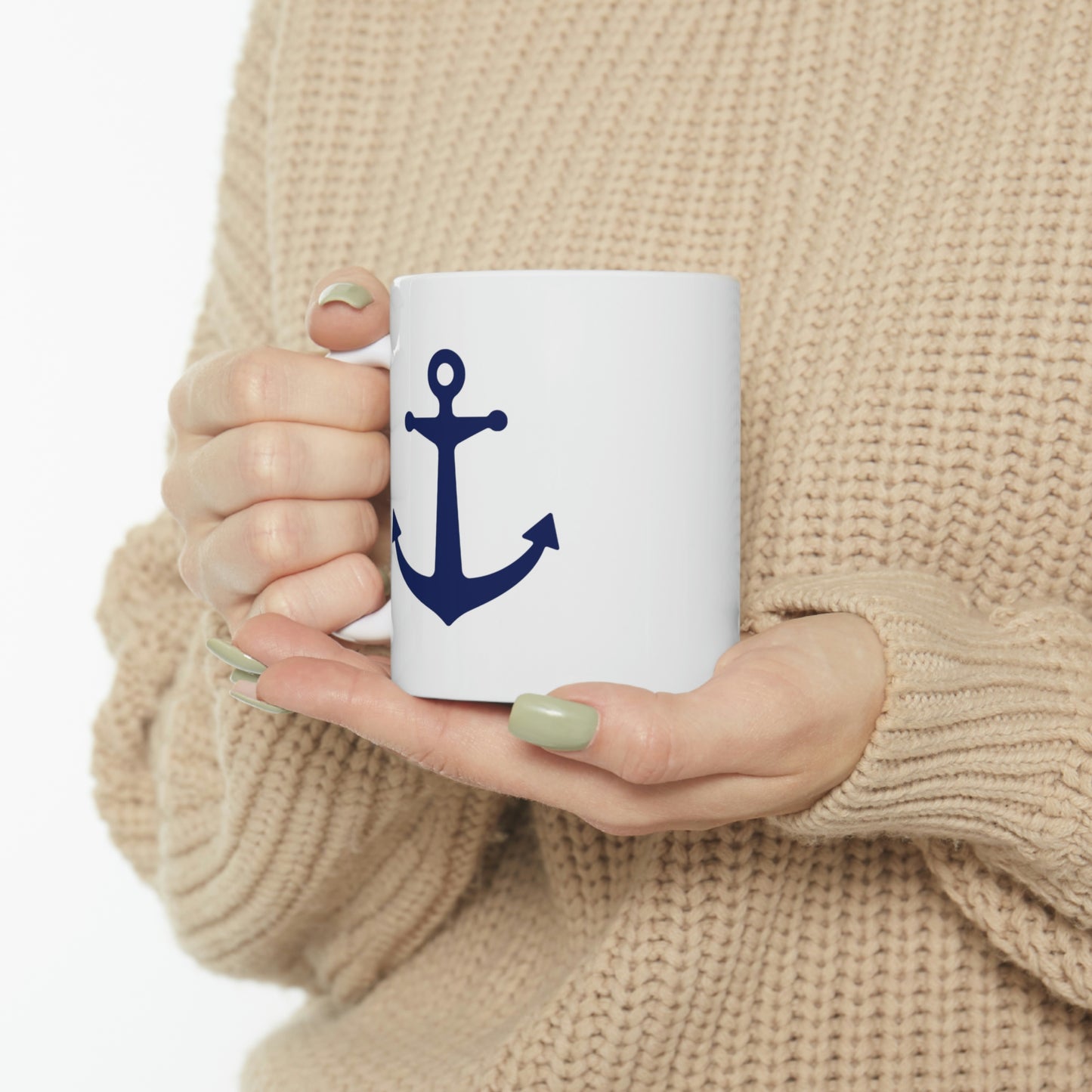 Woman in a cable knit sweater holding a white coffee mug with a navy blue anchor